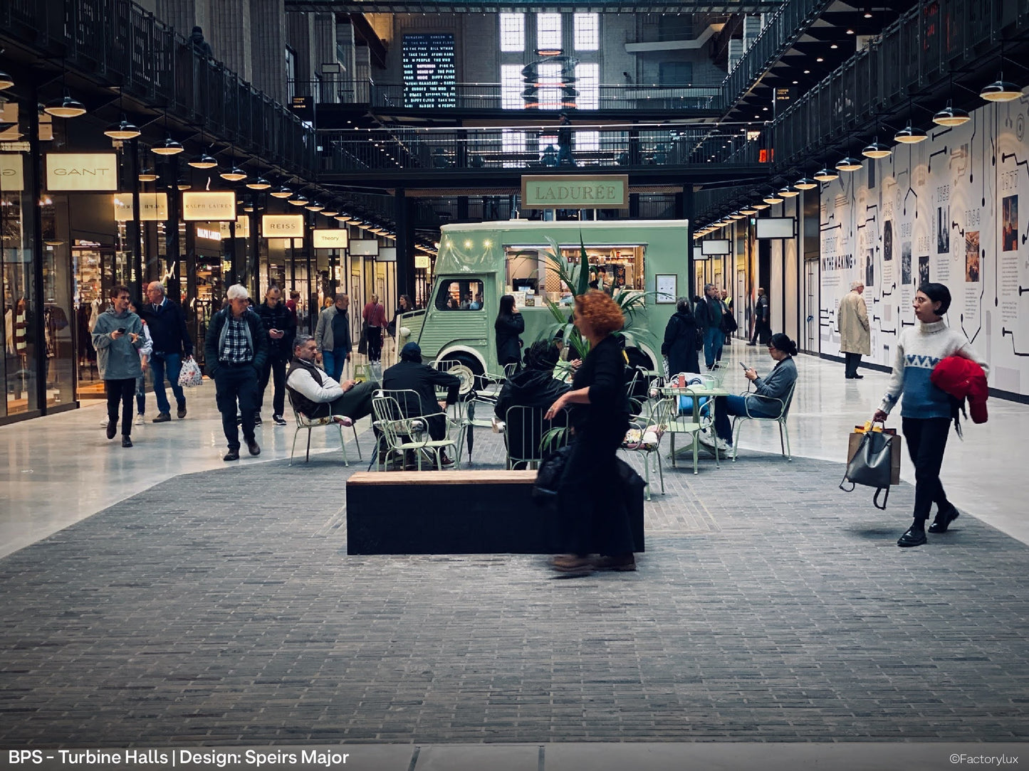 Rows of black architectural pendant lights, lighting up the pedestarian walkway at Battersea Power Station shopping mall