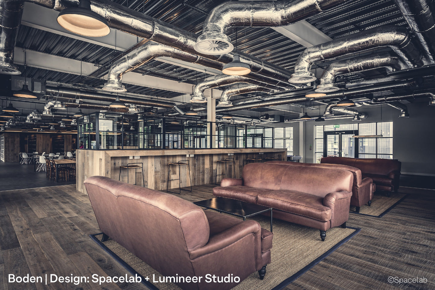 Track mounted pendant lights inside Boden's open plan office, lighting co-working desks, lockers and seating areas