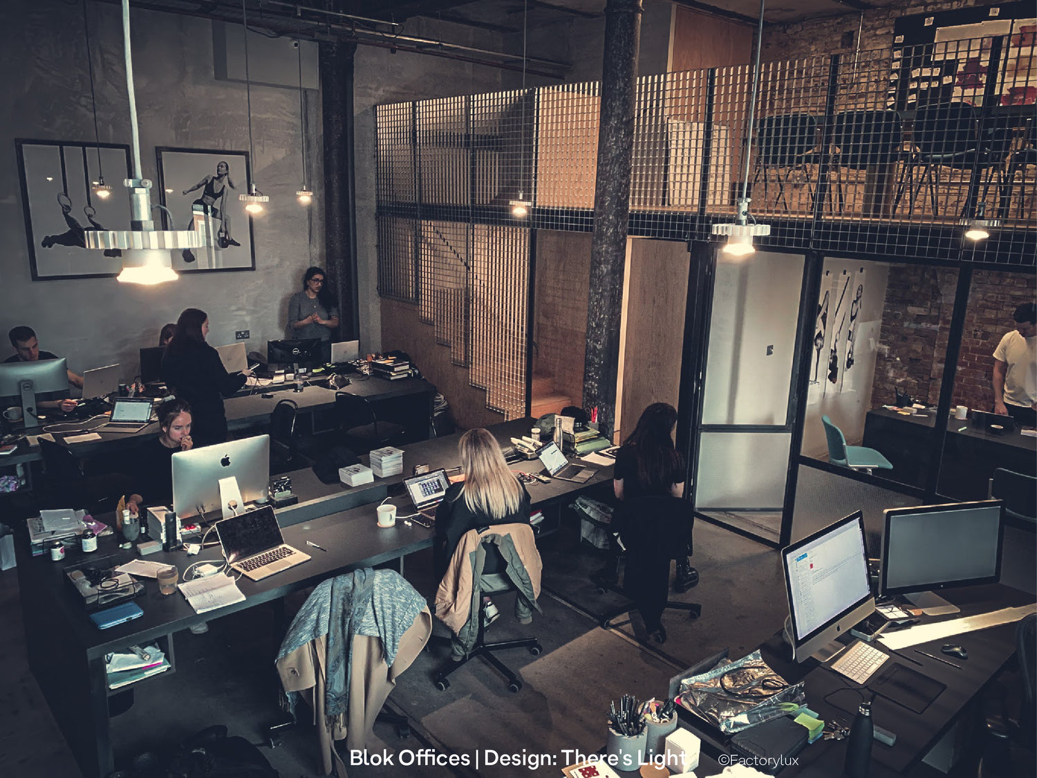 Office co-workers at desks in a industrial chic workspace interior with raw steel mesh, timber beams and open ceilings