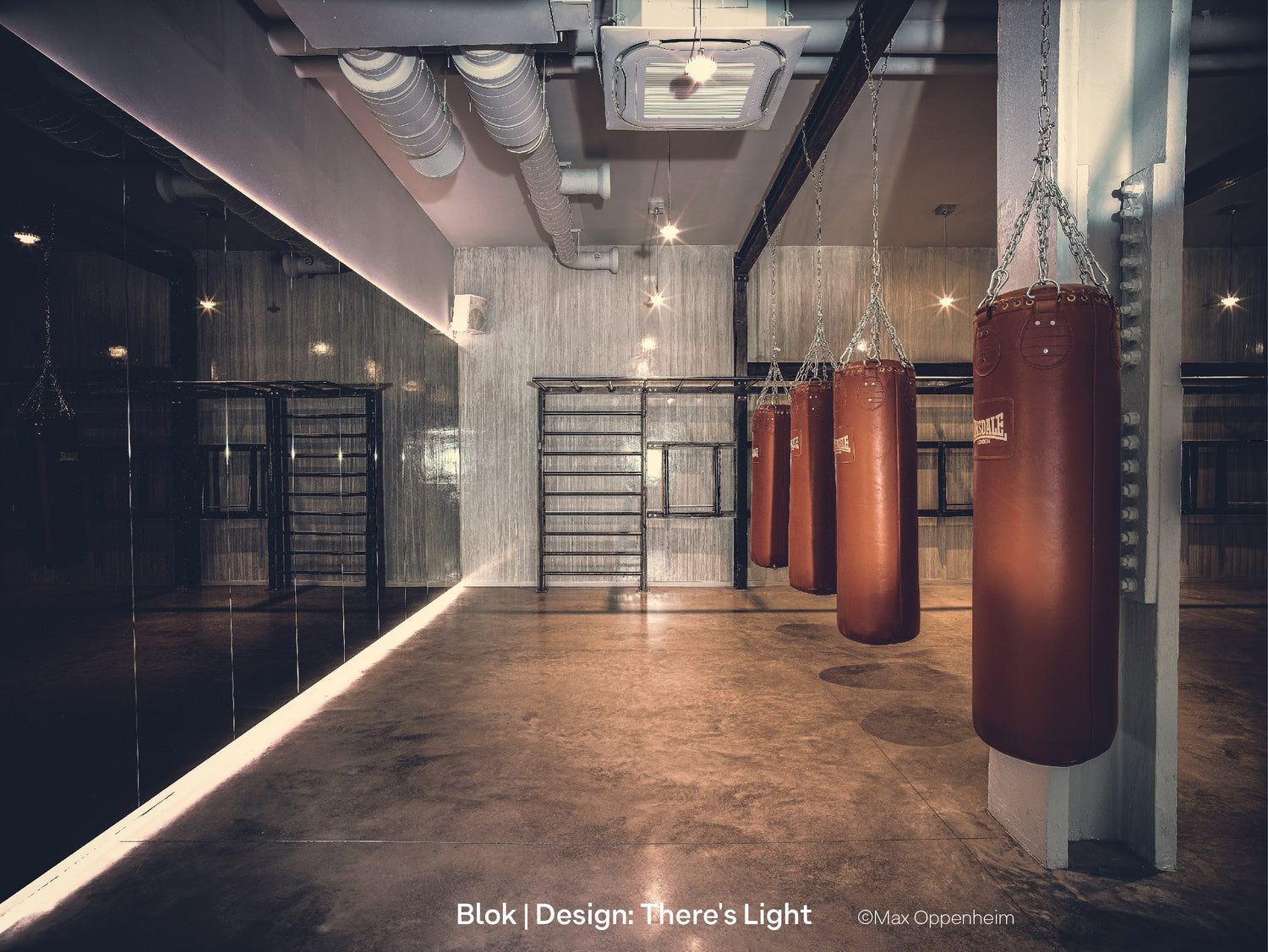 Punch bags hanging in a contemporary gym interior with raw concrete walls, HVAC and a mirror wall