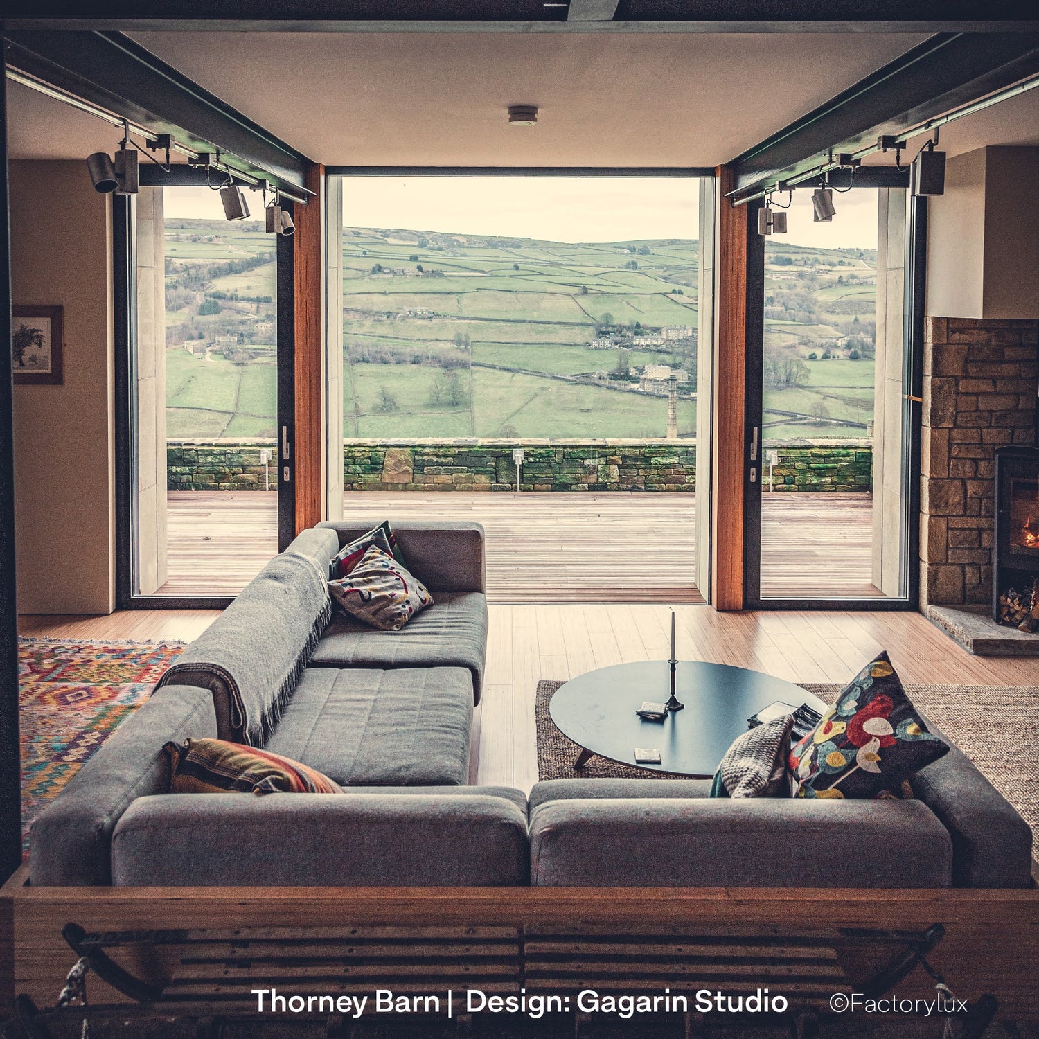 Low-impact barn conversion with natural timber interior design, sofa and architectural lighting with spotlights on pipe and tube