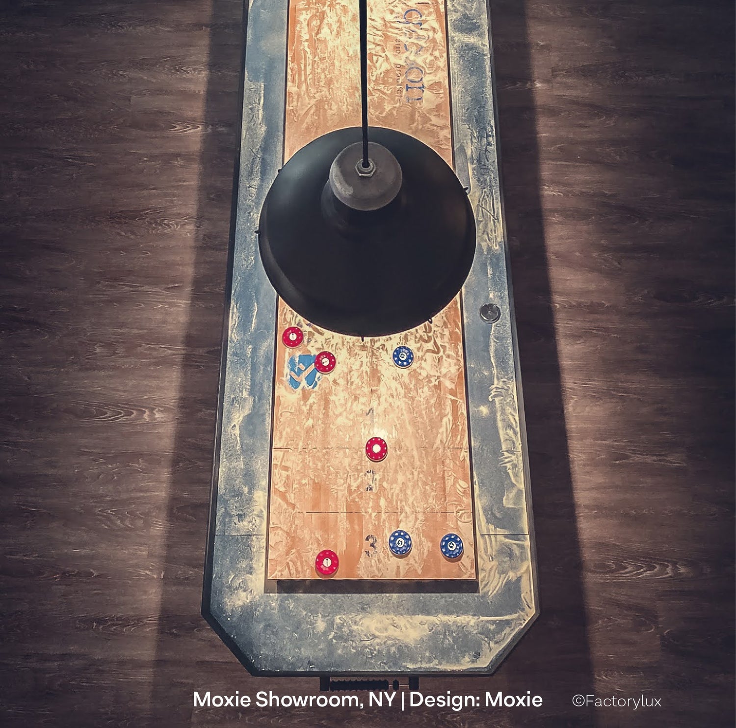 Specialist matt black pendant lights, hanging over and illuminating the playing surface of an American maple shuffle board