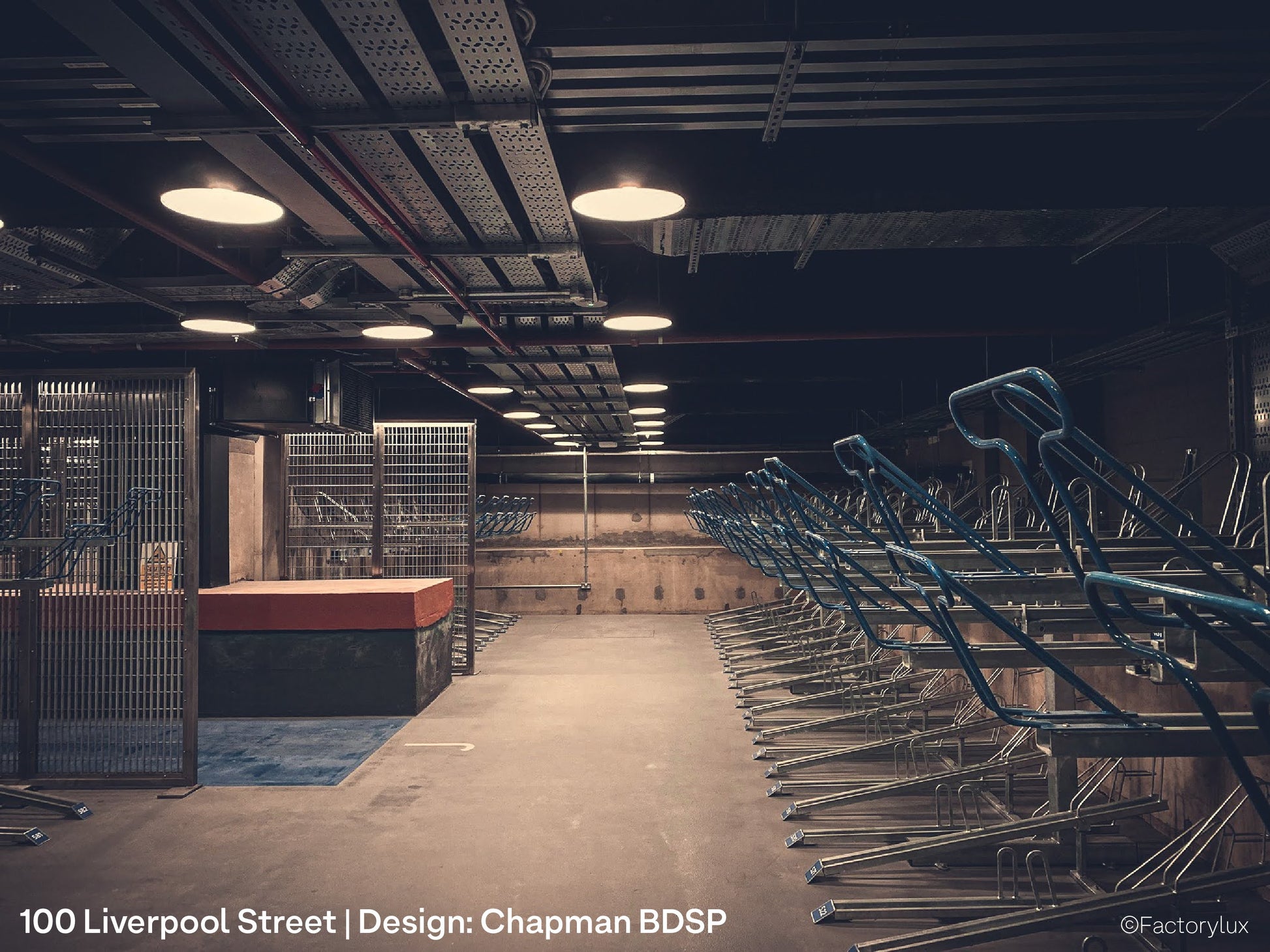 Safe bicycle storage with attractive pendant lighting in the underground concrete parking lot of an office development