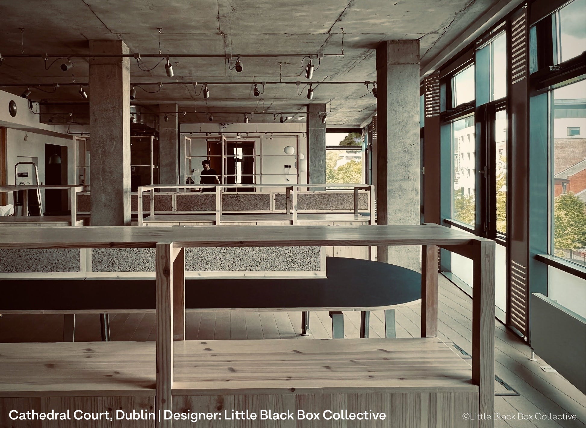 Pipe lighting and spotlights on the ceiling of a co-working and presentation space within a design office